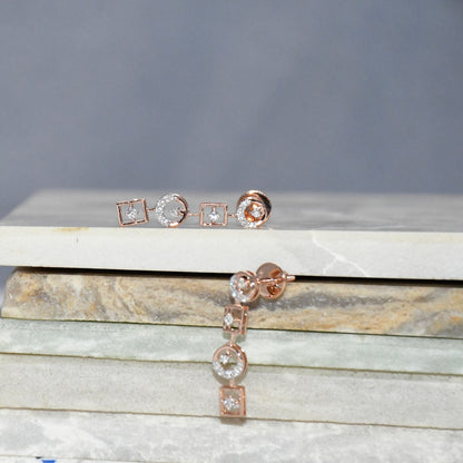 Rose gold earrings on a marble surface with a gray background