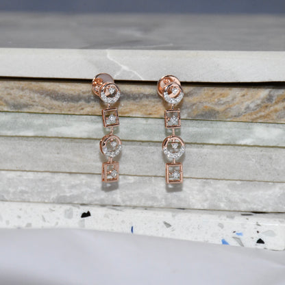 Rose gold earrings with diamonds on a marble surface