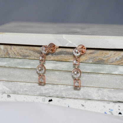 Rose gold earrings with clear diamonds on a marble surface