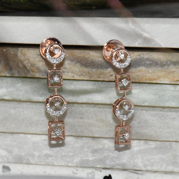 Rose gold earrings with clear diamonds on a marble surface
