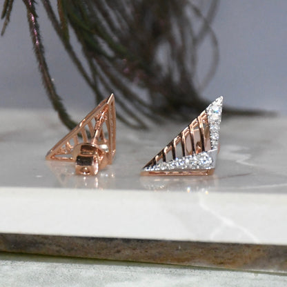 Gold and diamond earrings on a marble surface with a plant in the background.