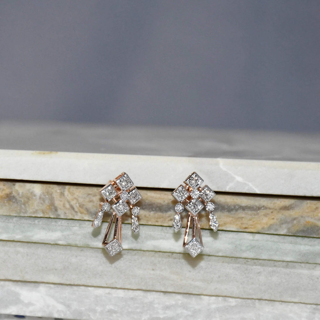 Pair of diamond earrings on a marble surface with a gray background