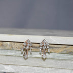 Pair of diamond earrings on a marble surface with a gray background