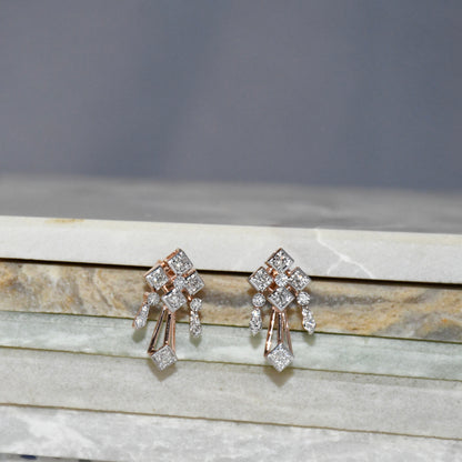 Pair of diamond earrings on a marble surface with a gray background