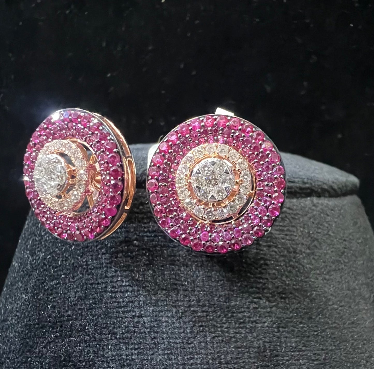 A pair of gold diamond stud earrings with a rose gold band on a black mannequin.