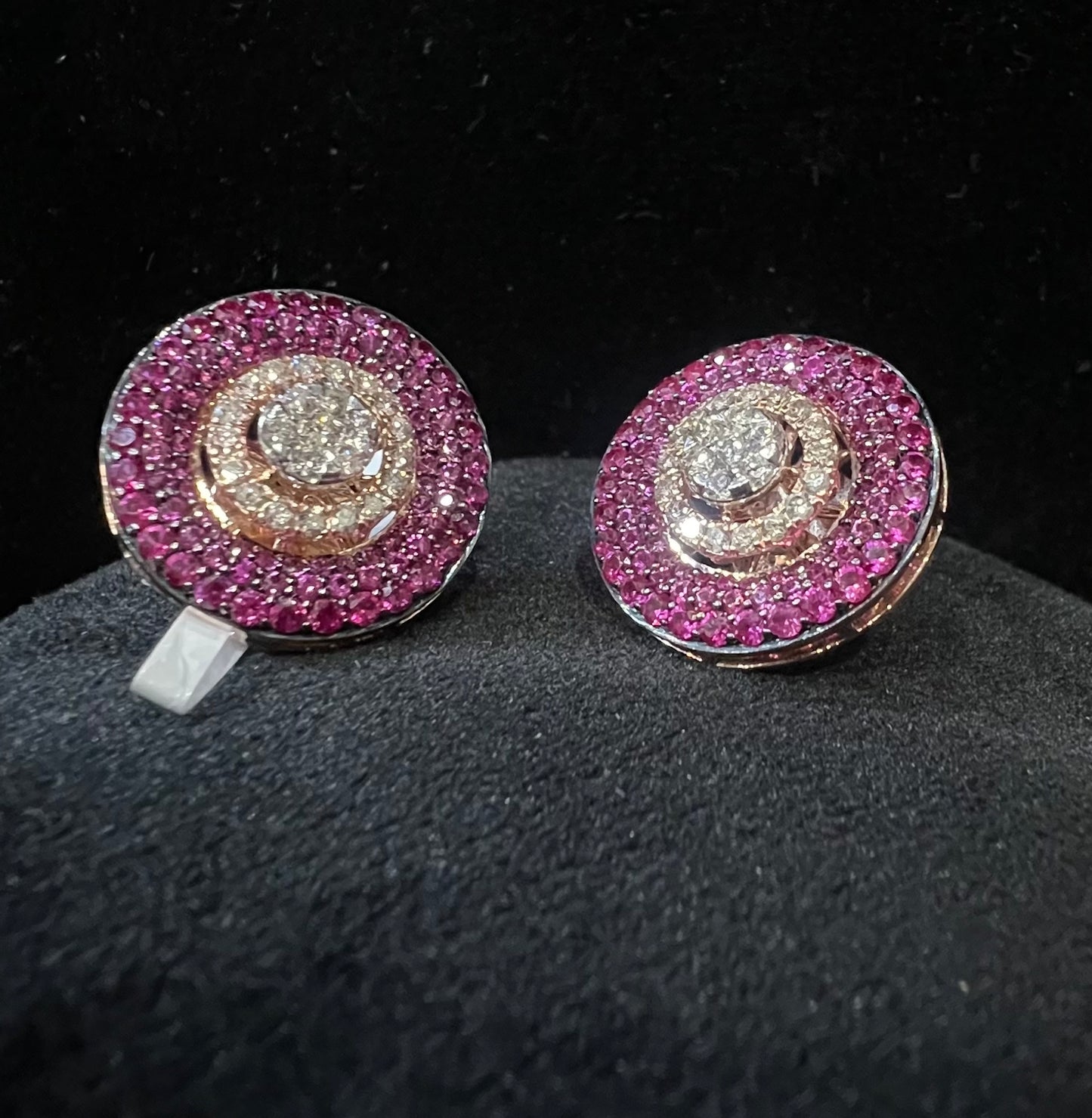 A pair of gold diamond stud earrings with a gold band on a black mannequin.