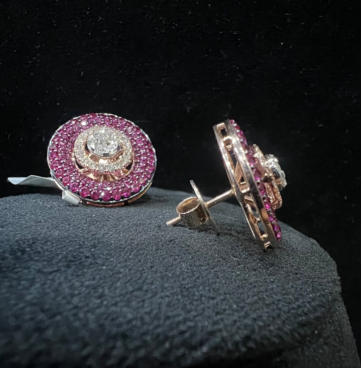 A pair of gold diamond stud earrings with a gold band on a black mannequin.