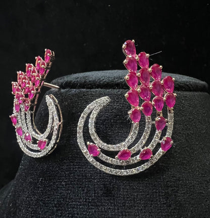 Pair of color stone and diamond swirl earrings with multiple pear-shaped color stones and round diamonds set in a circular design on a black display stand.