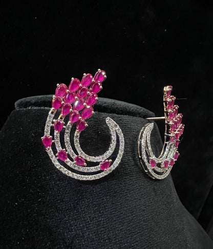 Pair of color stone and diamond swirl earrings with multiple pear-shaped color stones and round diamonds set in a circular design on a black display stand.