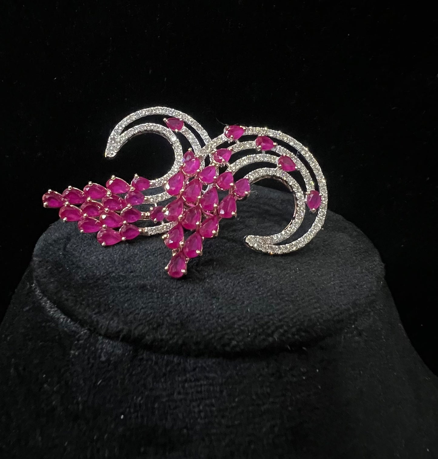 Pair of color stone and diamond swirl earrings with multiple pear-shaped color stones and round diamonds set in a circular design on a black display stand.