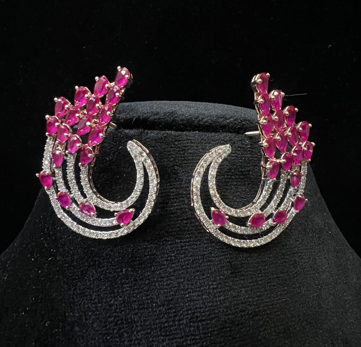 Pair of color stone and diamond swirl earrings with multiple pear-shaped color stones and round diamonds set in a circular design on a black display stand.