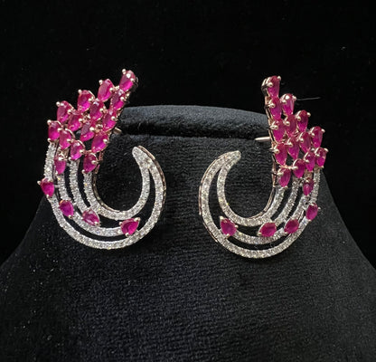 Pair of color stone and diamond swirl earrings with multiple pear-shaped color stones and round diamonds set in a circular design on a black display stand.
