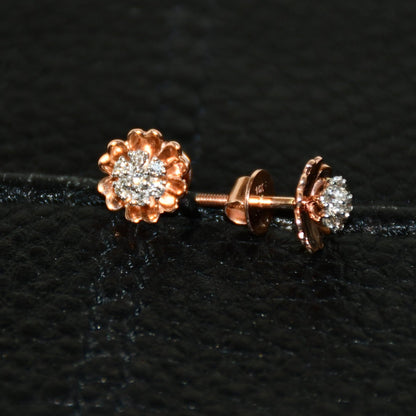 A pair of gold diamond earrings with a brilliant cut design, displayed against a black background.