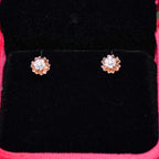 A pair of gold diamond earrings with a brilliant cut design, displayed in a jewelry box.