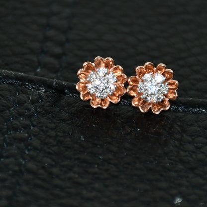 A pair of gold diamond earrings with a brilliant cut design, displayed against a black background.