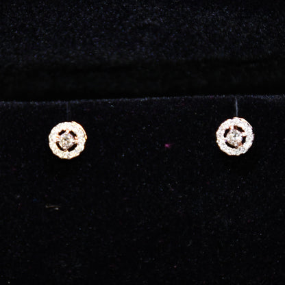 Pair of round halo cluster diamond earrings in gold with center diamonds and surrounding diamond halo, placed against a black background.