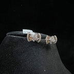 A pair of gold diamond earrings with a round cut design on a mannequin stand.