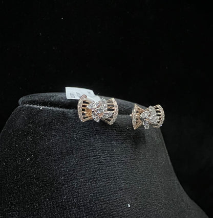 A pair of gold diamond earrings with a round cut design on a mannequin stand.