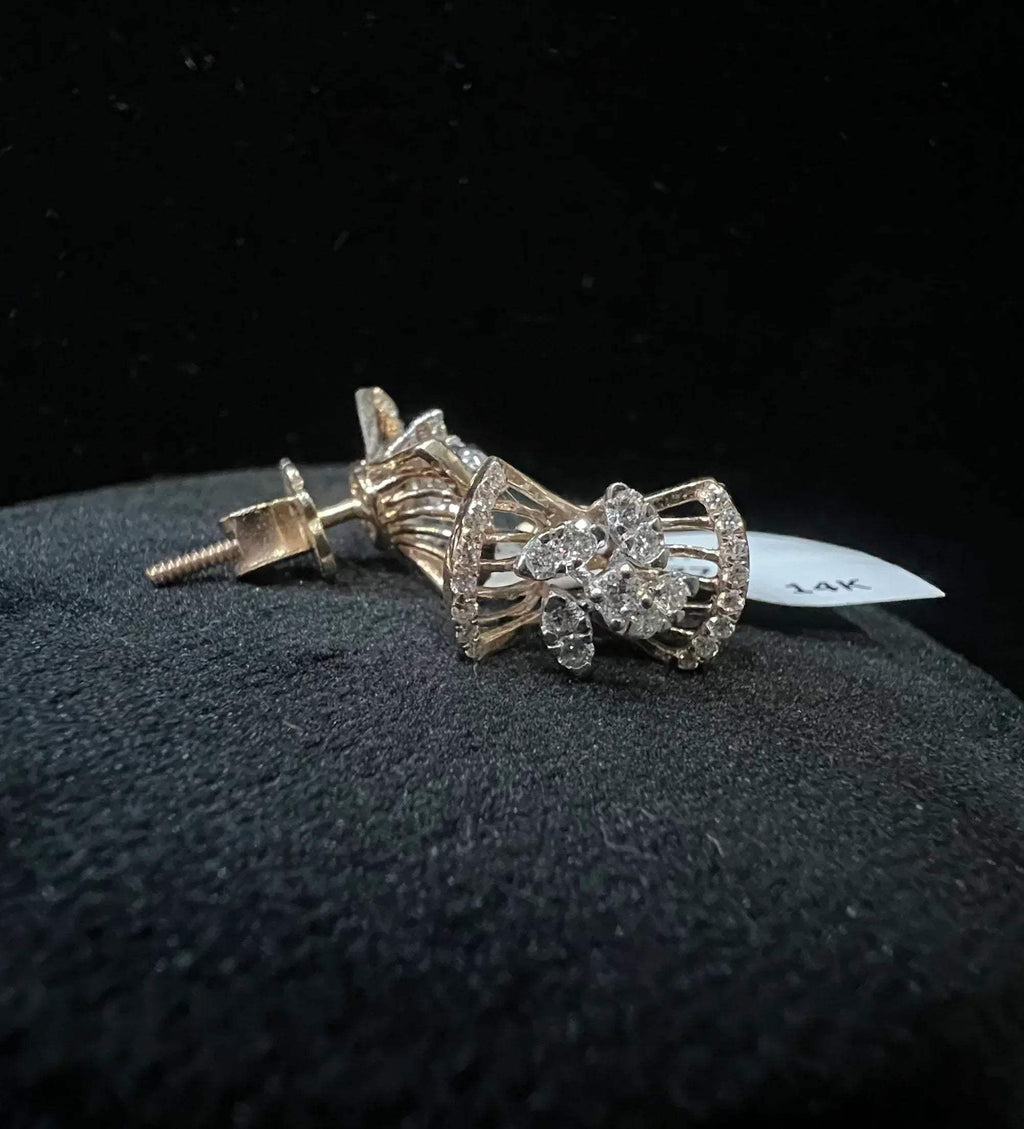 A pair of gold diamond earrings with a round cut design on a mannequin stand.
