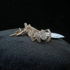 A pair of gold diamond earrings with a round cut design on a mannequin stand.