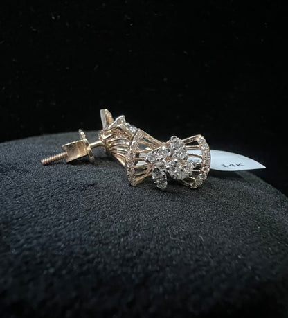 A pair of gold diamond earrings with a round cut design on a mannequin stand.