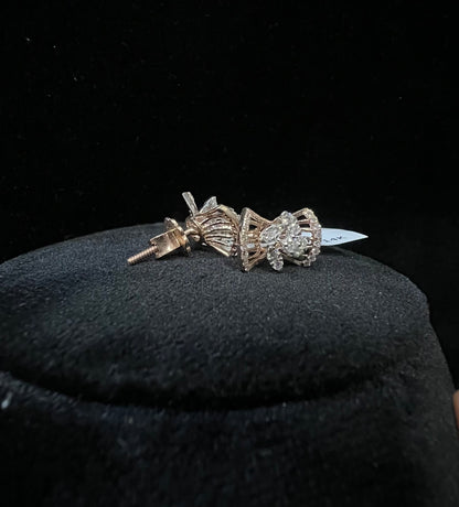 A pair of gold diamond earrings with a round cut design on a mannequin stand.