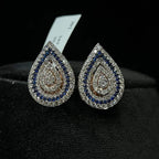 A pair of gold diamond earrings with a geometric pattern, displayed on a mannequin bust.