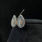 A pair of gold diamond earrings with a geometric pattern, displayed on a mannequin bust.