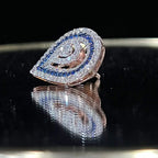 A pair of gold diamond earrings with a geometric pattern, displayed on a reflective surface.