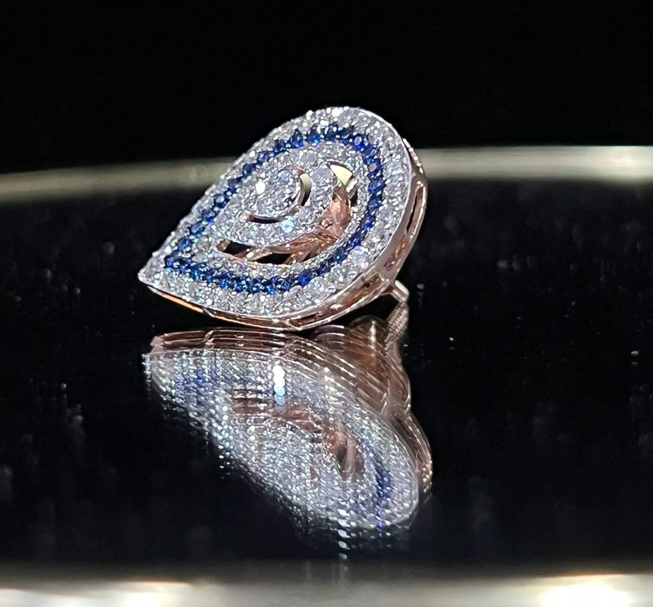 A pair of gold diamond earrings with a geometric pattern, displayed on a reflective surface.