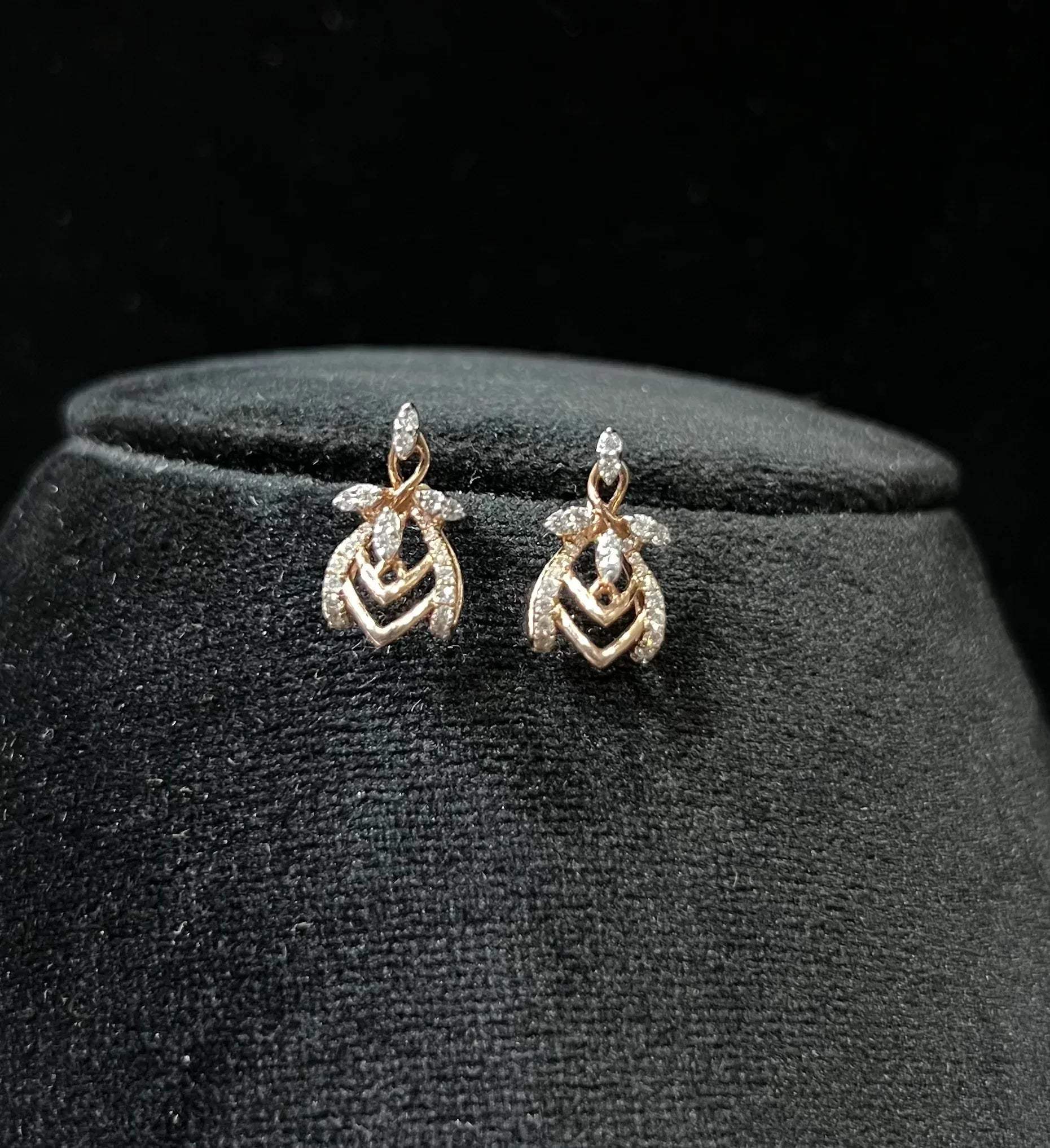 A pair of diamond earrings with a rose gold or gold color finish, featuring a V-shaped design with diamond embellishments.