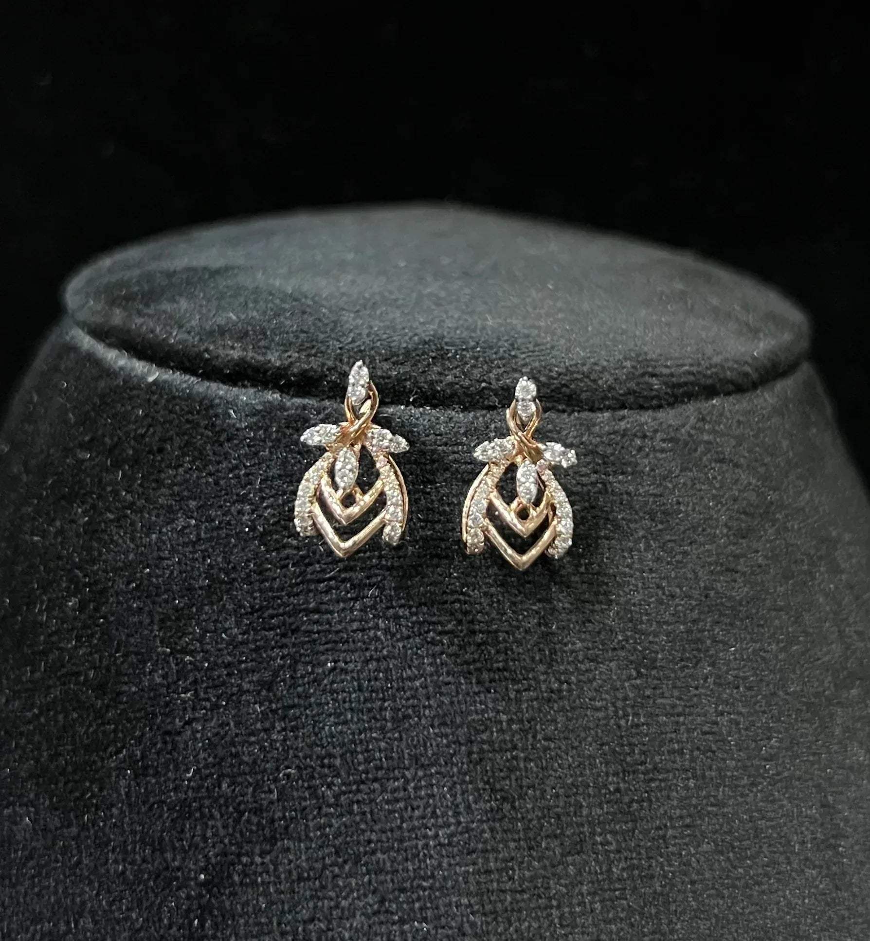 A pair of diamond earrings with a rose gold or gold color finish, featuring a V-shaped design with diamond embellishments.
