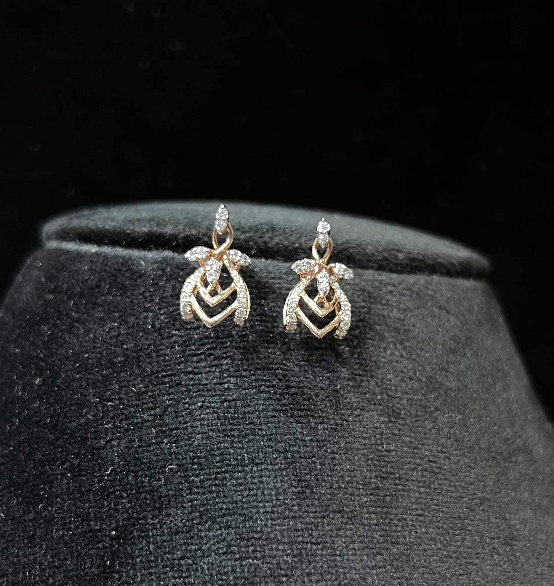 A pair of diamond earrings with a rose gold or gold color finish, featuring a V-shaped design with diamond embellishments.