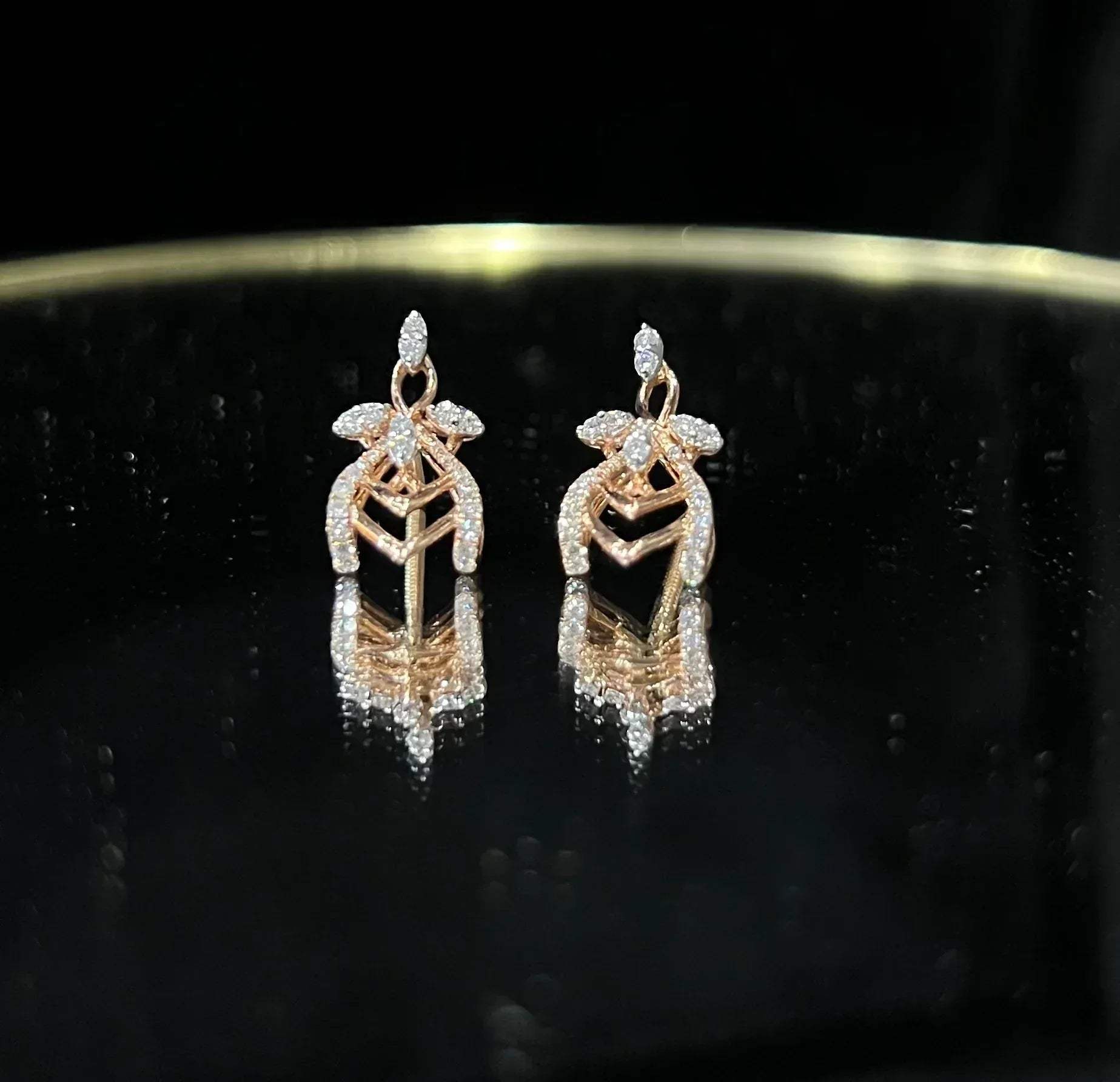 A pair of diamond earrings with a rose gold or gold color finish, featuring a V-shaped design with diamond embellishments.