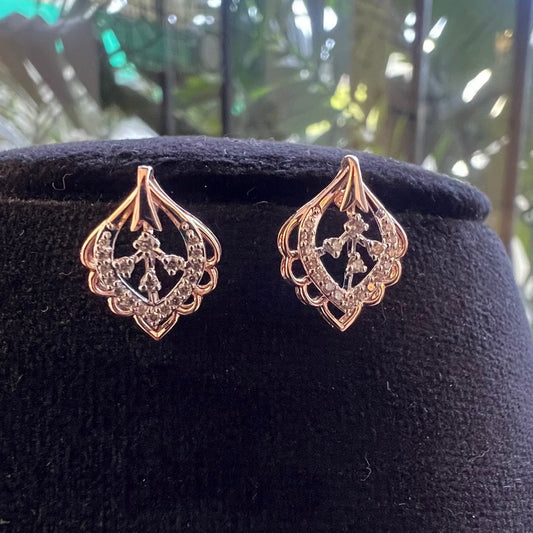 A pair of diamond stud earrings displayed on a black stand, with a mannequin jewelry stand in the background.