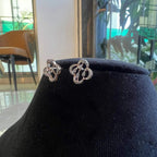 Pair of clover bloom diamond stud earrings in gold, designed with open quatrefoil petals and diamond accents.
