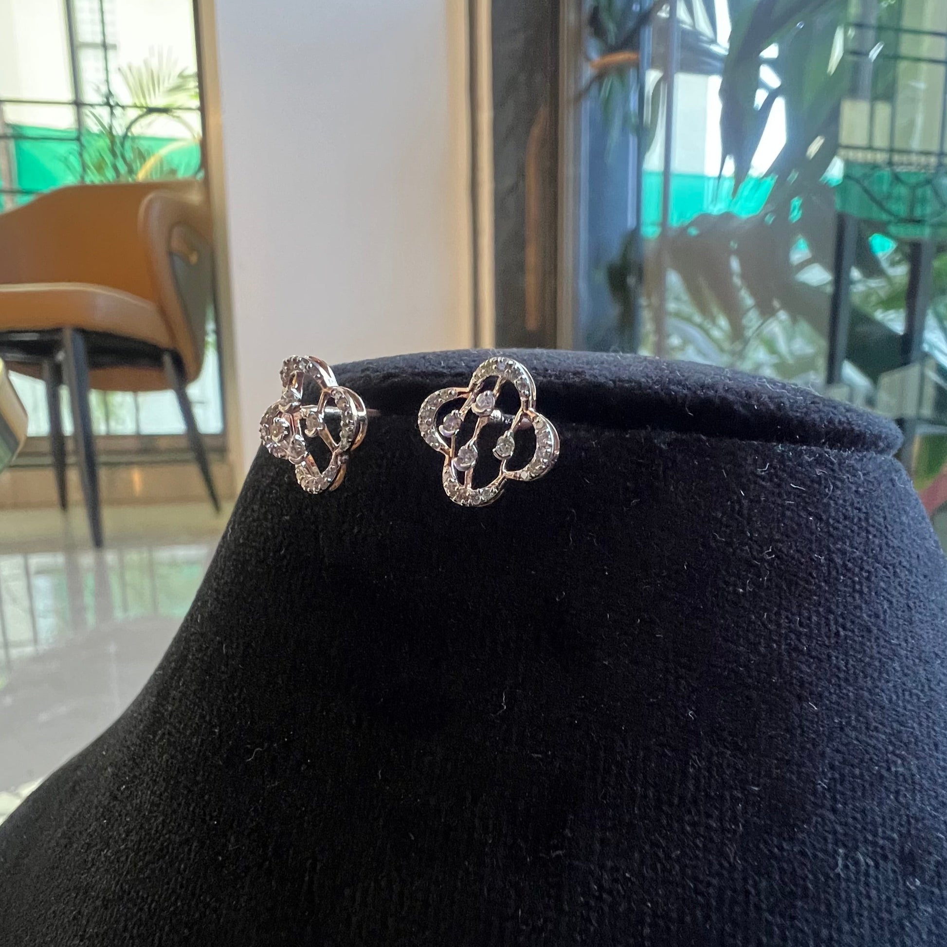 Pair of clover bloom diamond stud earrings in gold, designed with open quatrefoil petals and diamond accents.