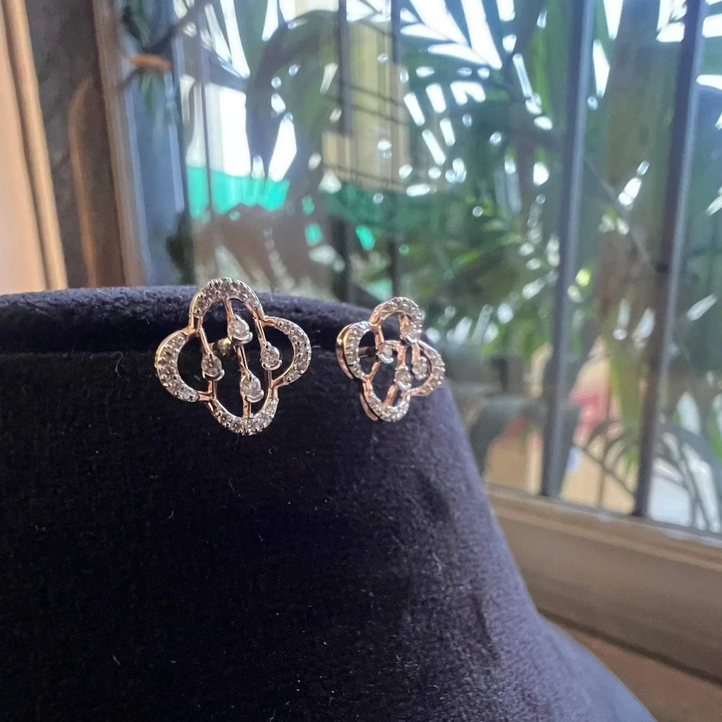 Pair of clover bloom diamond stud earrings in gold, designed with open quatrefoil petals and diamond accents.