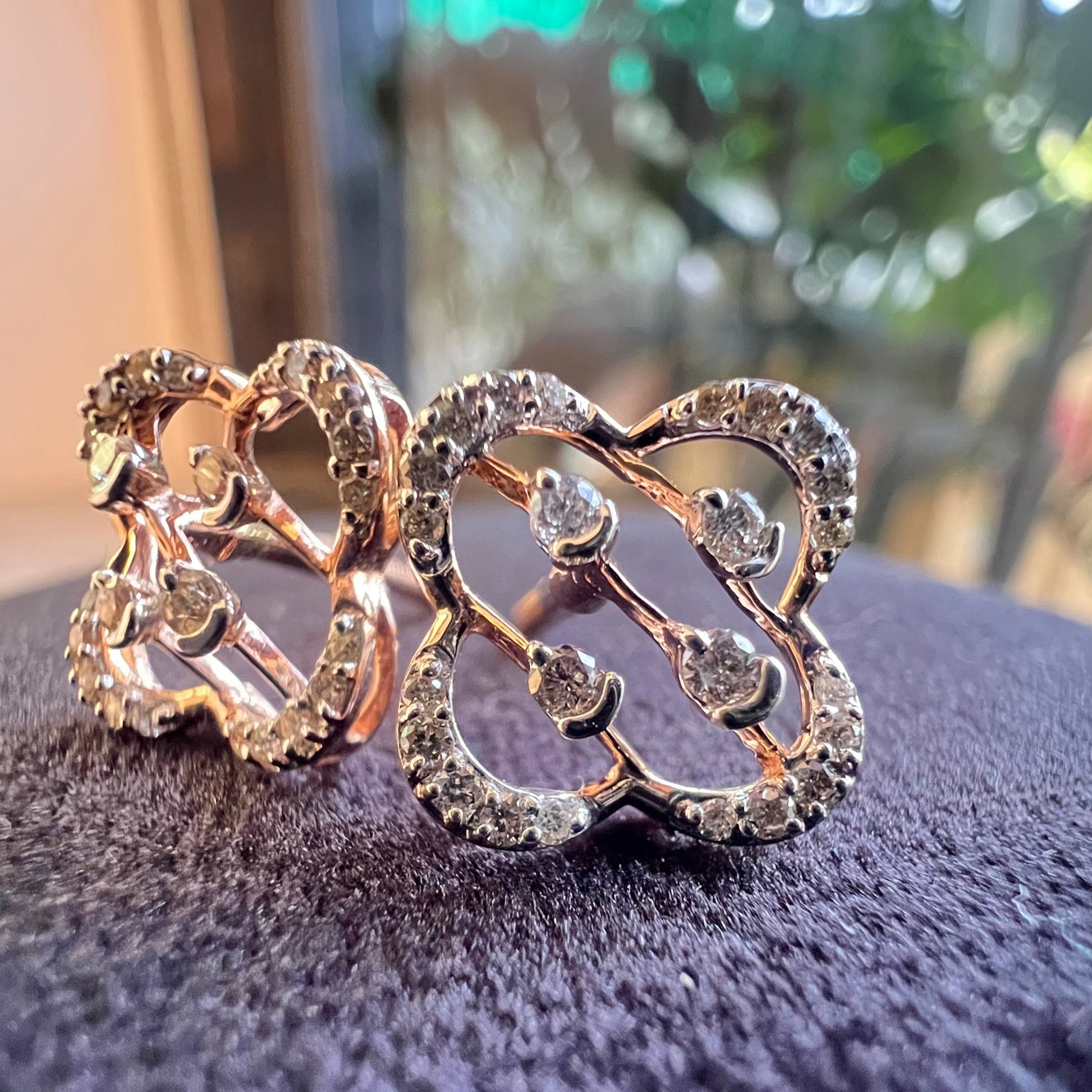 Close-up view of clover bloom diamond stud earrings in gold with openwork floral design and sparkling diamonds.
