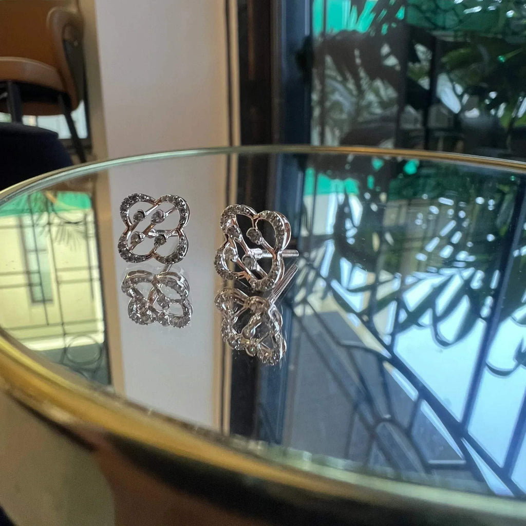 view of clover bloom diamond earrings in gold with openwork floral design and sparkling diamonds.