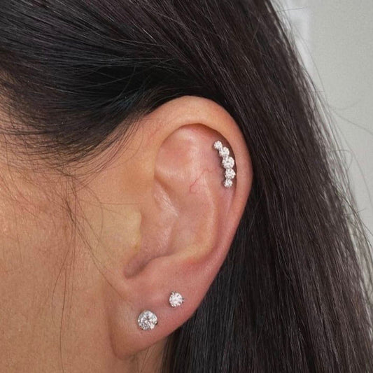 Close-up of an ear wearing three diamond stud earrings with dark hair.