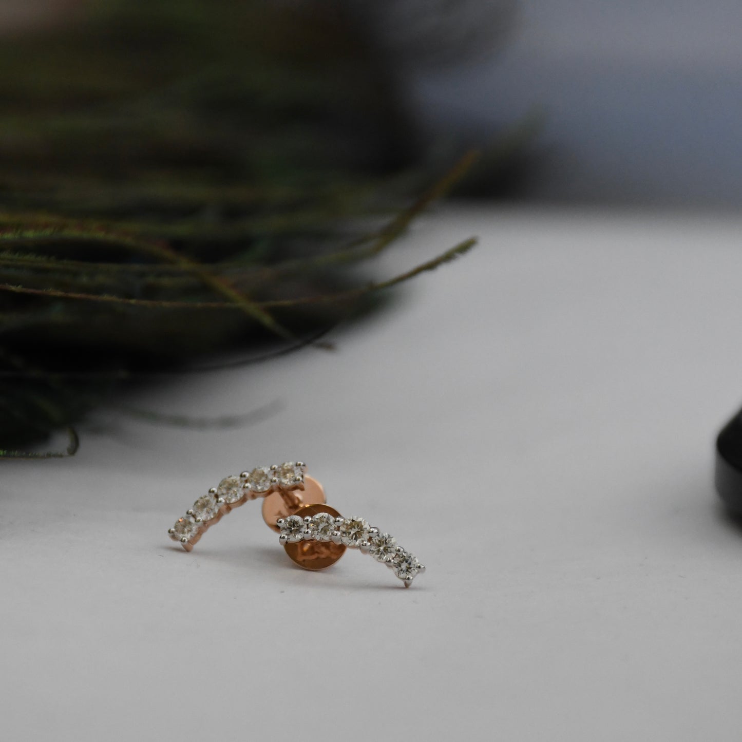 Rose gold earrings with real diamond accents on a neutral background