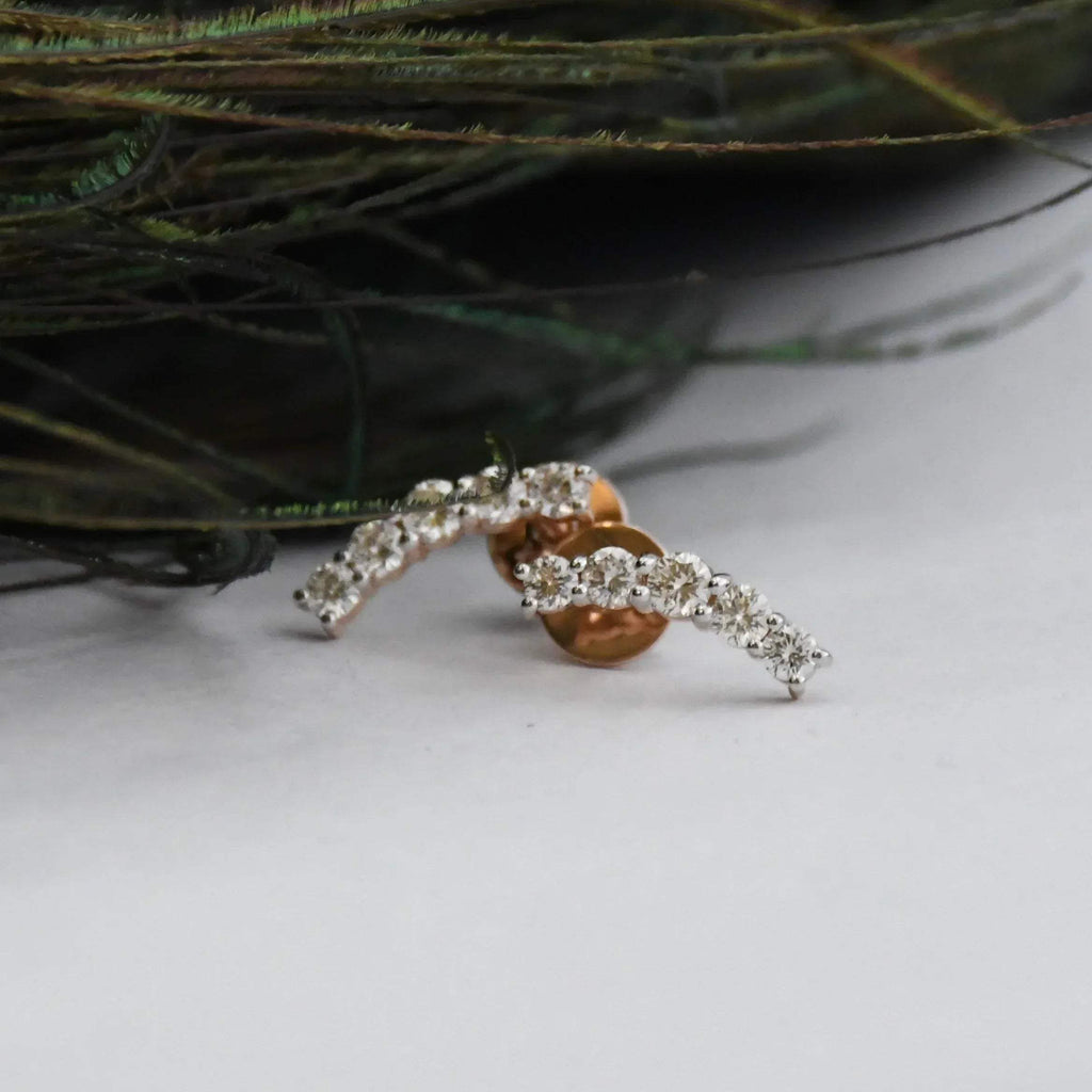 real diamond stud earrings on a white surface with greenery in the background