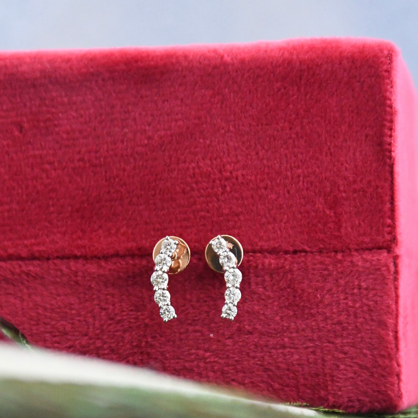 Diamond earrings on a red velvet stand with a blurred background