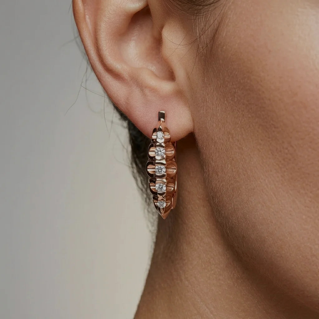 Close-up of a rose gold hoop earring with diamonds on an ear.