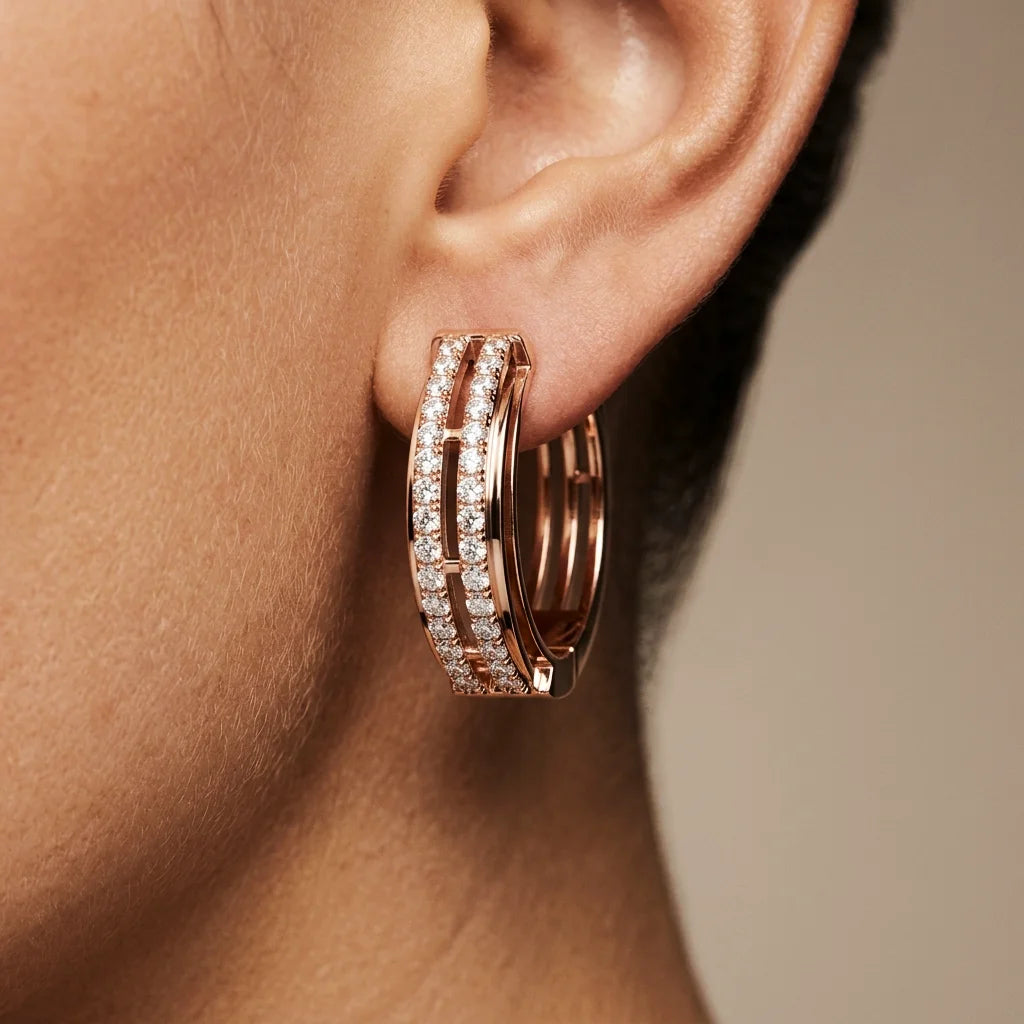 Rose gold hoop earrings with clear diamonds worn by a person.