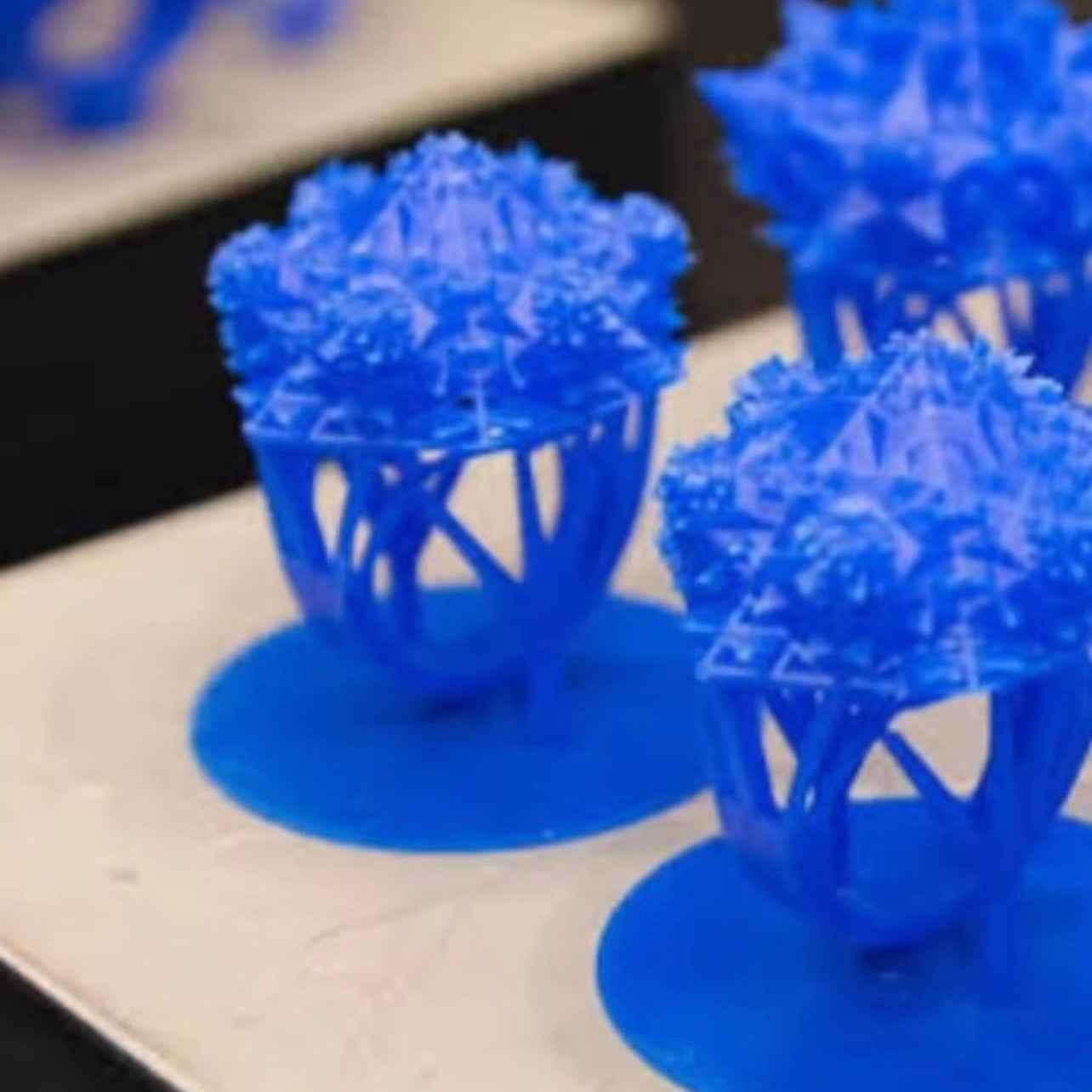 Blue 3D-printed flower models on a wooden surface