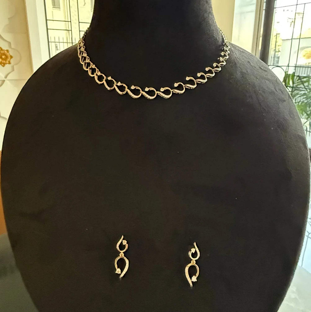 A gold diamond necklace with a chain link design, displayed on a mannequin bust, accompanied by a pair of matching earrings with a geometric design.