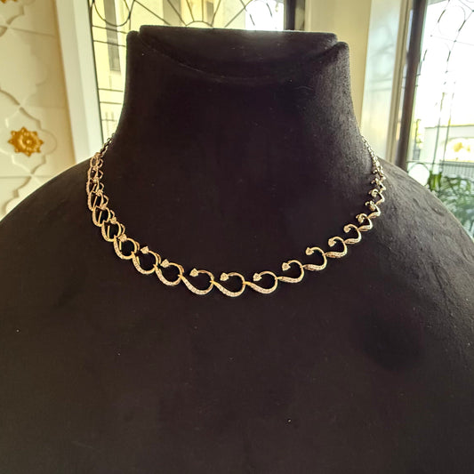 A gold diamond necklace with a chain link design, displayed on a mannequin bust.