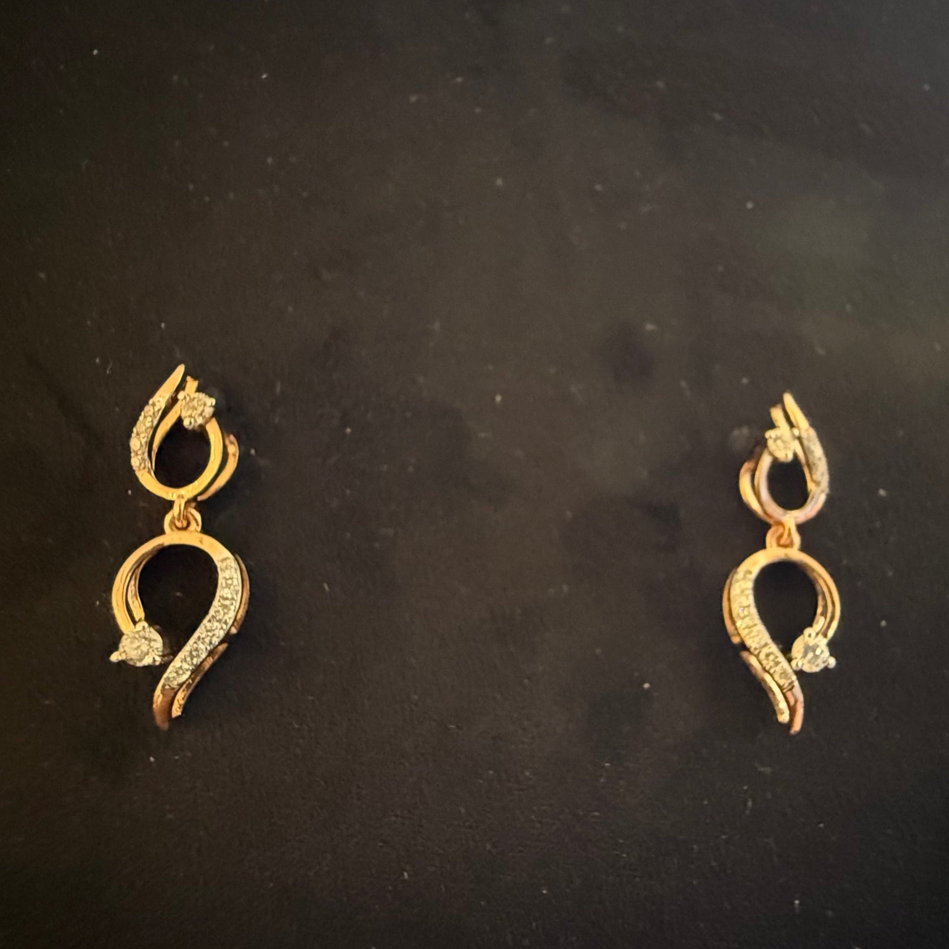 A gold diamond earrings with a chain link design, displayed on a mannequin bust.